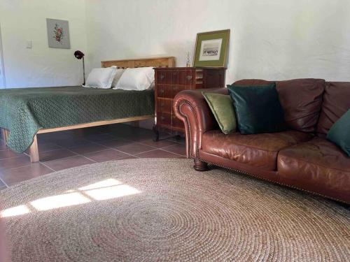- un salon avec un canapé et un lit dans l'établissement The Cottage on West, à Greyton