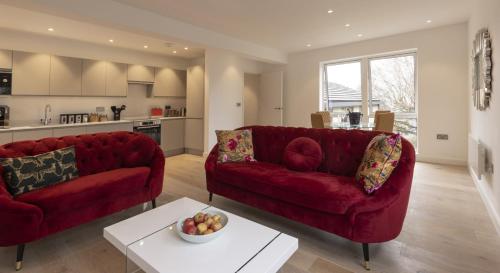 a living room with two red couches and a table at Charlecote House in Bath