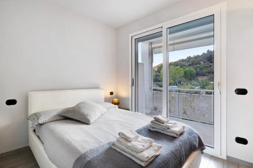 Dormitorio blanco con cama y ventana grande en Casa Caterina, en Finale Ligure
