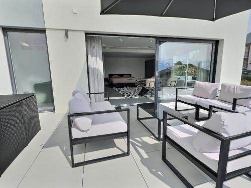 a balcony with white chairs and a living room at Attica Résidences, Lausanne in Saint-Sulpice