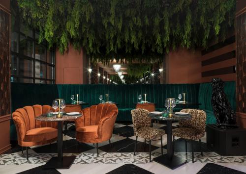 a restaurant with tables and chairs and a green wall at NYX Esperia Palace Hotel Athens by Leonardo Hotels in Athens