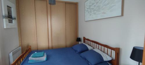 Dormitorio pequeño con cama azul y almohadas azules en les pieds dans l'eau à 50 mètres de la mer, en Saint-Quay-Portrieux