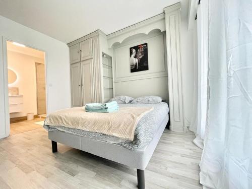 een witte slaapkamer met een bed in een kamer bij Appartement 2 pièces proche Enghien-Les-Bains in Soisy-sous-Montmorency
