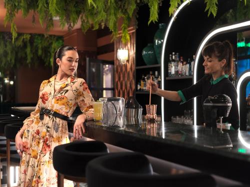 a woman standing at a bar with a bartender at NYX Esperia Palace Hotel Athens by Leonardo Hotels in Athens