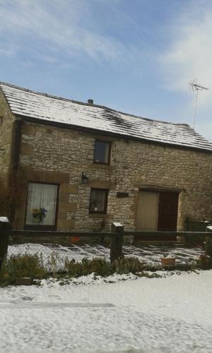 uma casa de pedra com neve em frente em Old Coach House em Matlock
