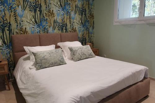 un lit avec des draps blancs et des oreillers dans une chambre dans l'établissement La Petite Germaine, à Fontaine-sur-Ay