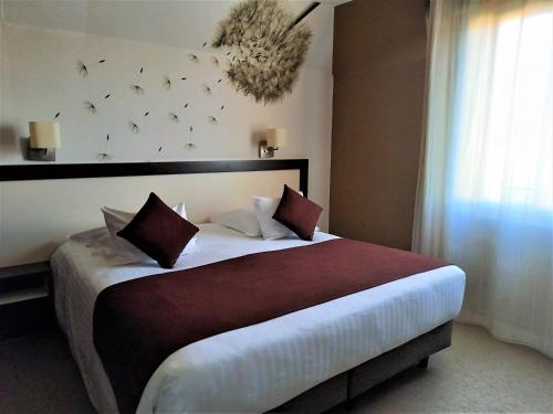 a hotel room with a large bed with pillows at Quality Hotel La Marebaudière Vannes Centre in Vannes