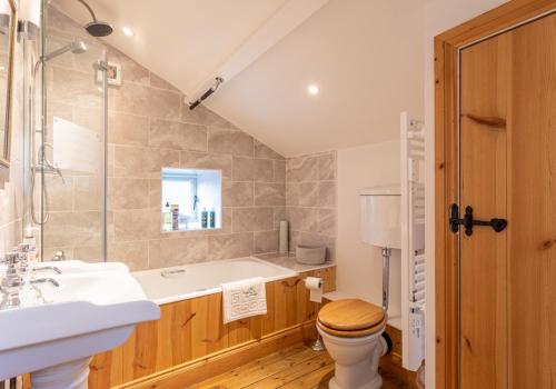 a bathroom with a tub and a toilet and a sink at Ivy Cottage in Low Eskcleth