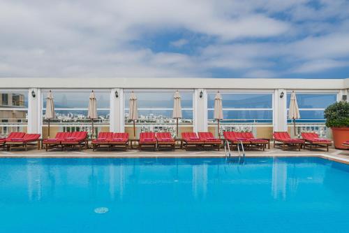 a swimming pool with red chairs and a view of the city at The Arkin Colony Hotel in Kérynia