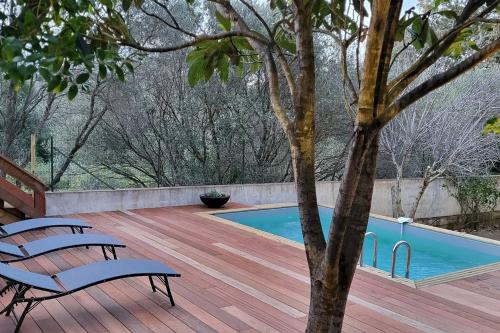 een houten terras met een zwembad en twee banken bij Casa Marcelli 4 in Porto-Vecchio