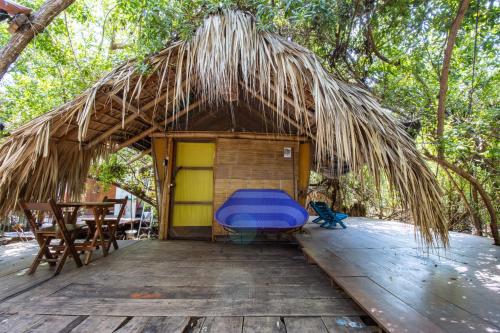 a thatched hut with a blue bench on a wooden deck at Posada Corazon Mazunte in Mazunte
