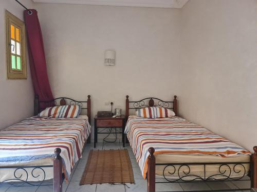 - deux lits assis l'un à côté de l'autre dans une pièce dans l'établissement Riad BAB ALMADINA, à Marrakech