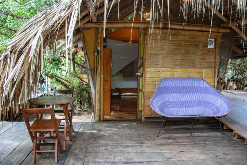 a room with a purple bed and a table and chairs at Posada Corazon Mazunte in Mazunte