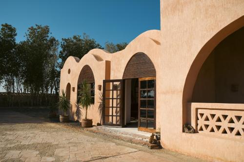a building with arches and a door with a potted plant at Tzila Bahariya in Az Zaytūn