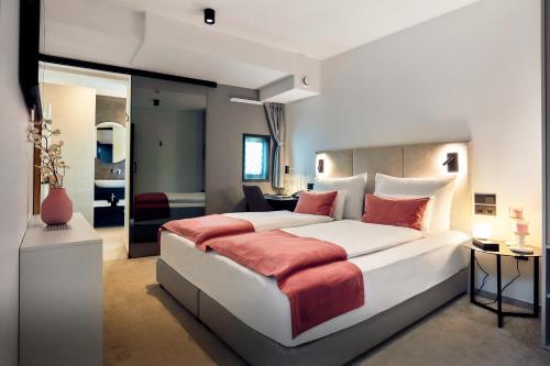 sypialnia z dużym białym łóżkiem z czerwonymi poduszkami w obiekcie The Hotel Ljubljana w Lublanie