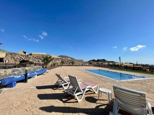 two lawn chairs sitting next to a swimming pool at Rural house with private pool, BBQ, and views of the Atlantic Ocean in Tenerife South in San Miguel de Abona