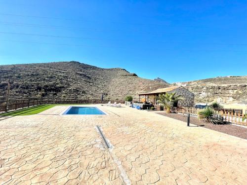 a house with a swimming pool and a mountain at Rural house with private pool, BBQ, and views of the Atlantic Ocean in Tenerife South in San Miguel de Abona