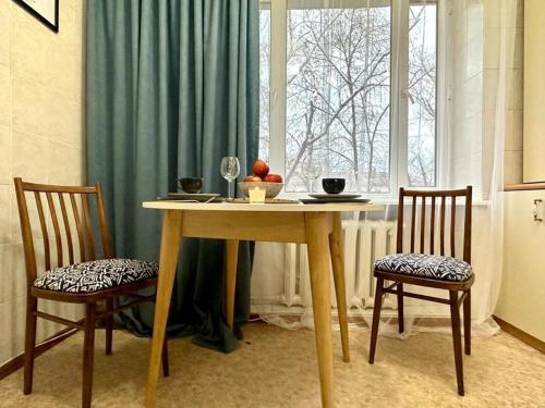 a dining room table with two chairs and a window at Квартира на Атакенте у Выставки in Almaty