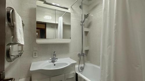 a white bathroom with a sink and a shower at Квартира на Атакенте у Выставки in Almaty