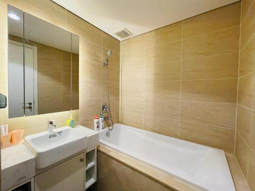uma casa de banho com uma banheira, um lavatório e um espelho. em VNRooms - 2BR Vinhomes D'Capitale/ LAKE VIEW/ 23Fl em Hanói
