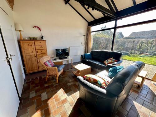 a living room with a black leather couch and chairs at Boerenslag 42 in Sint Maartensvlotbrug