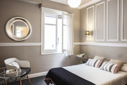 Schlafzimmer mit einem Bett, einem Fenster und einem Spiegel in der Unterkunft AinB B&B Eixample-Muntaner in Barcelona