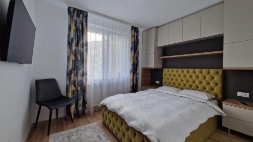 a bedroom with a large bed and a chair at CENTRAL 6 in Topliţa