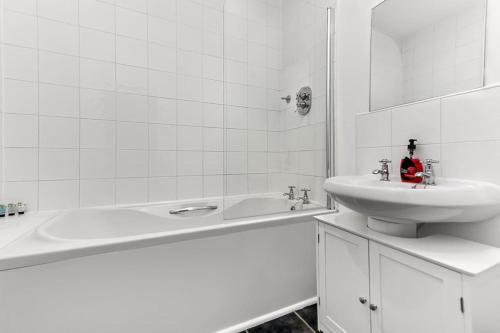 a white bathroom with a sink and a bath tub at Large Group & Contractor Booking! Duplex w/Parking in Milton Keynes