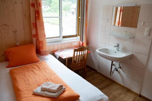 a small room with a bed and a sink at Haus Alpenrose Obertraun in Obertraun