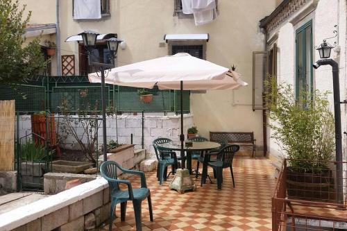 eine Terrasse mit einem Tisch, Stühlen und einem Sonnenschirm in der Unterkunft Casa San Francesco in Agnone