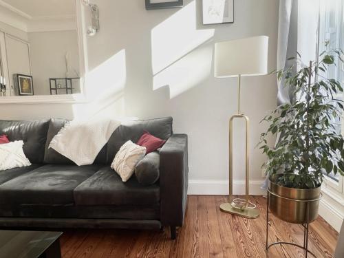 a black leather couch in a living room with a plant at Sublime Appartement de 105 m2 dans l'hyper centre avec Terrasse et parking à 5 min de la mer in Nice