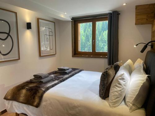 une chambre avec un lit avec des draps blancs et des oreillers dans l'établissement Le Petit Cham - Cosy and Stylist with Balcony View, à Morzine