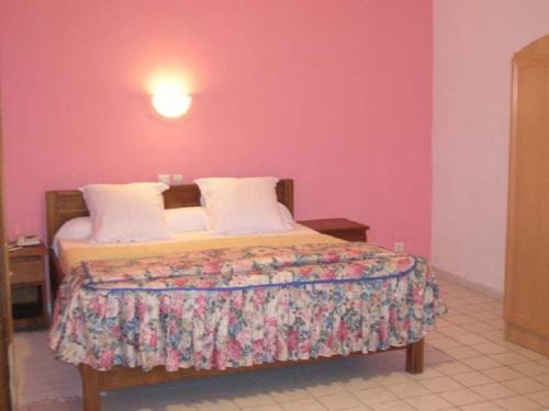 a bedroom with a bed with a pink wall at Residence Saint-Jacques Bord de Mer in Mpita