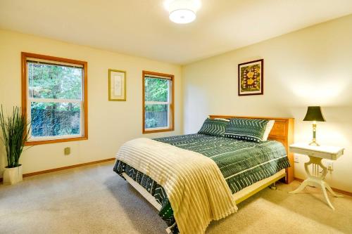a bedroom with a bed and a table and two windows at Milwaukie Home with Covered Porch Dogs Welcome! in Milwaukie