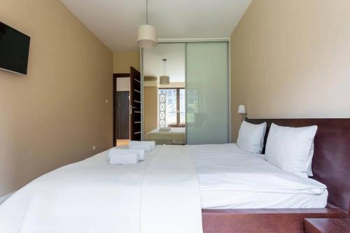 1 dormitorio con 1 cama blanca grande y espejo en GA-Rondo Daszynskiego&Siedmiogrodzka 1, en Varsovia