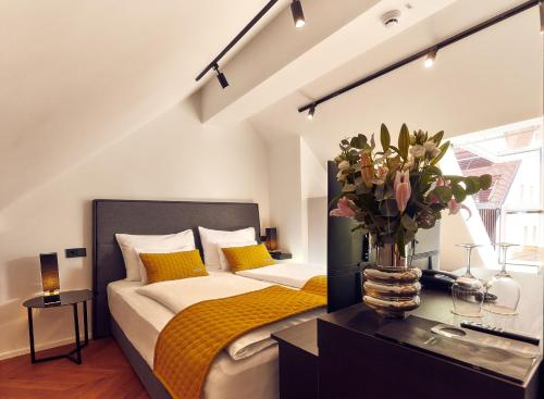 a bedroom with a bed with a vase of flowers at The Hotel Ljubljana in Ljubljana