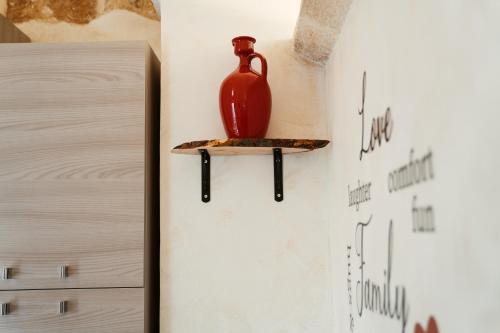 a red vase sitting on a shelf on a wall at My Family Home in Francavilla Fontana