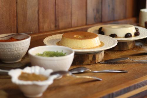 a table with bowls and plates of food and spoons at POUSADA SERTÃO DA BOCAINA in Cunha