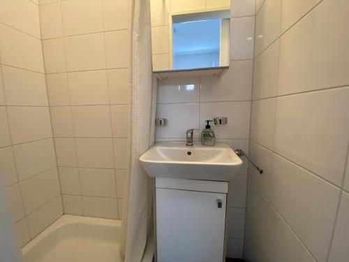 a white bathroom with a sink and a tub at De Zeekreeft in Katwijk aan Zee