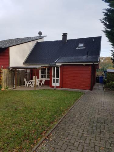 a red house with a table and chairs in a yard at Laras Ferienhaus in Worpswede