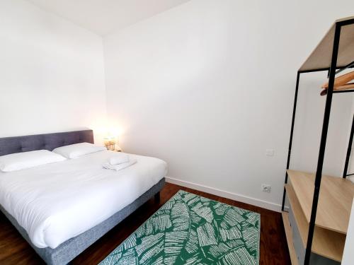 Cette petite chambre comprend un lit blanc et un tapis. dans l'établissement Plateau d'Angoulême proche bus et commerces, à Angoulême