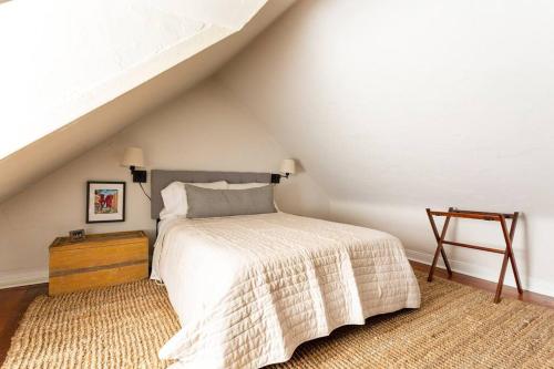 Dormitorio blanco con cama y mesa de madera en Saint Davids Cottage in Manayunk, Walk to Train, Main Street en Filadelfia