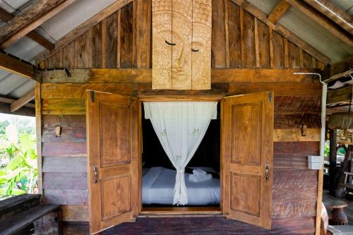 een bed in een houten kast met een gordijn bij Suk Sabai Homestay in Sukhothai