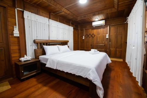 a bedroom with a large bed in a room with wooden walls at Suk Sabai Homestay in Sukhothai