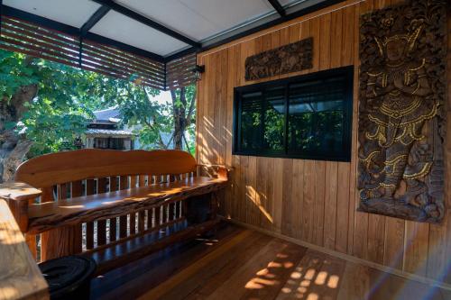a wooden bench in a room with a window at Suk Sabai Homestay in Sukhothai