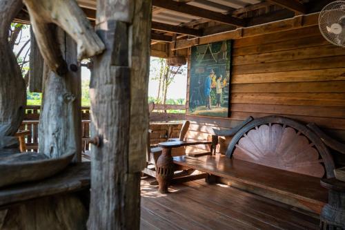 a wooden cabin with a bench and a painting on the wall at Suk Sabai Homestay in Sukhothai