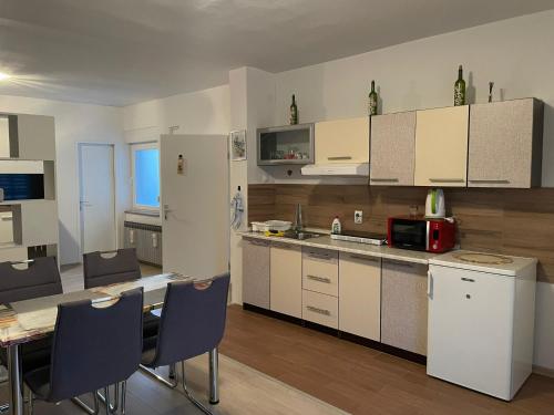 cocina con armarios blancos, mesa y sillas en Studio apartman Happiness en Ždralovi