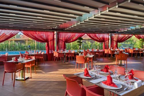 a restaurant with tables and chairs and red curtains at Megasaray Club Belek in Belek