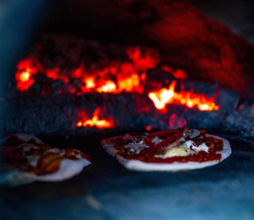 two pizzas in front of a fire oven at Bracken Yurt at Walnut Farm Glamping in Netherbury