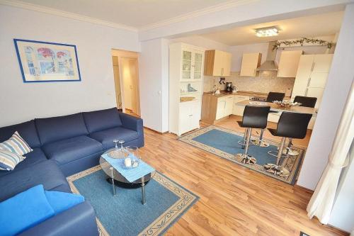 uma sala de estar com um sofá azul e uma cozinha em Möwe Whg 1 em Grömitz